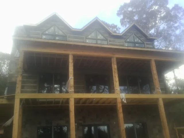 Dormers and porch framing on a large log home under construction — Roof Coating work by our crew in Bay Pines