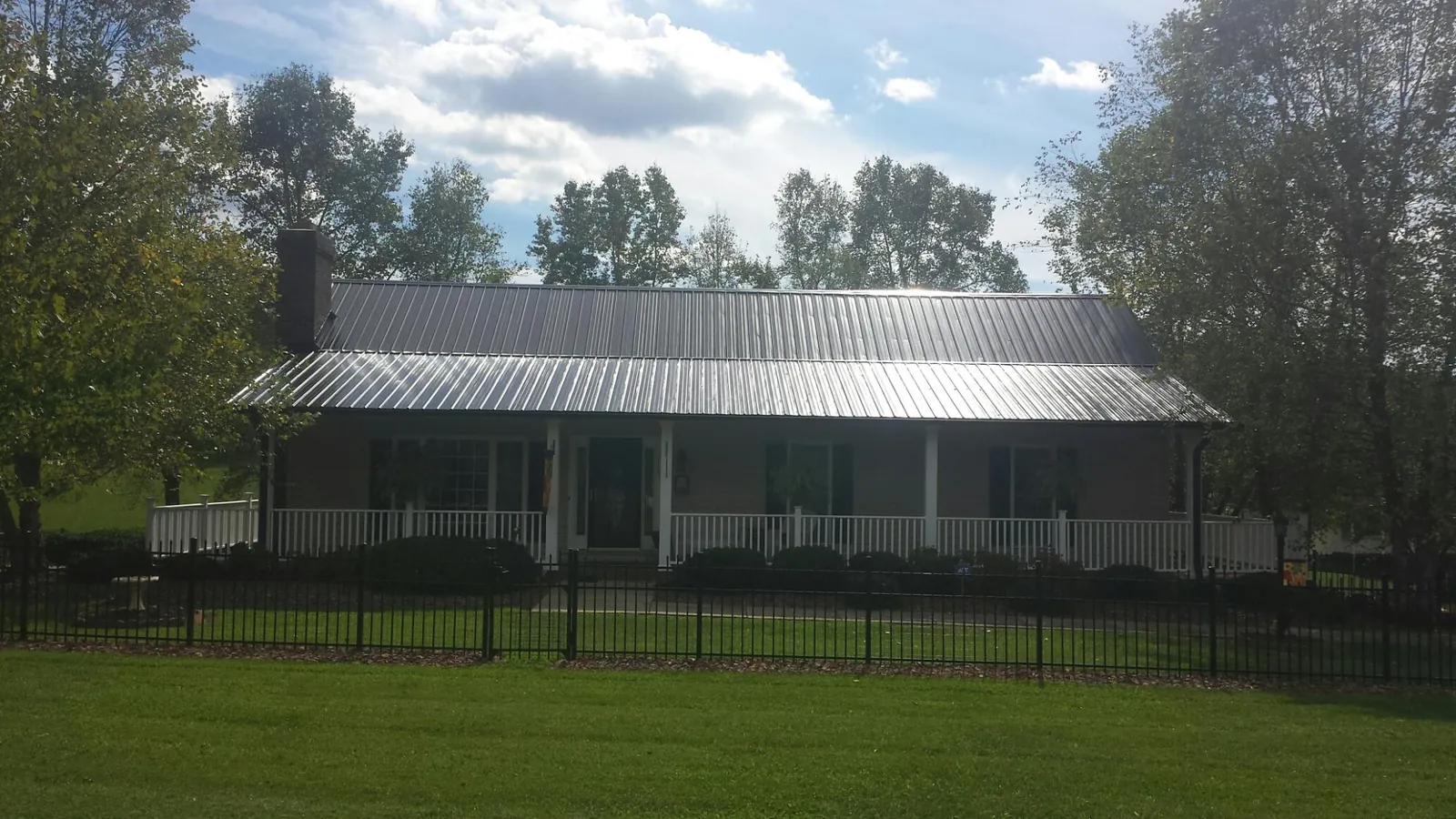 Gray metal roof on a brick ranch with a full width front porch — Gutter Guard Installation work by our crew in Bay Pines