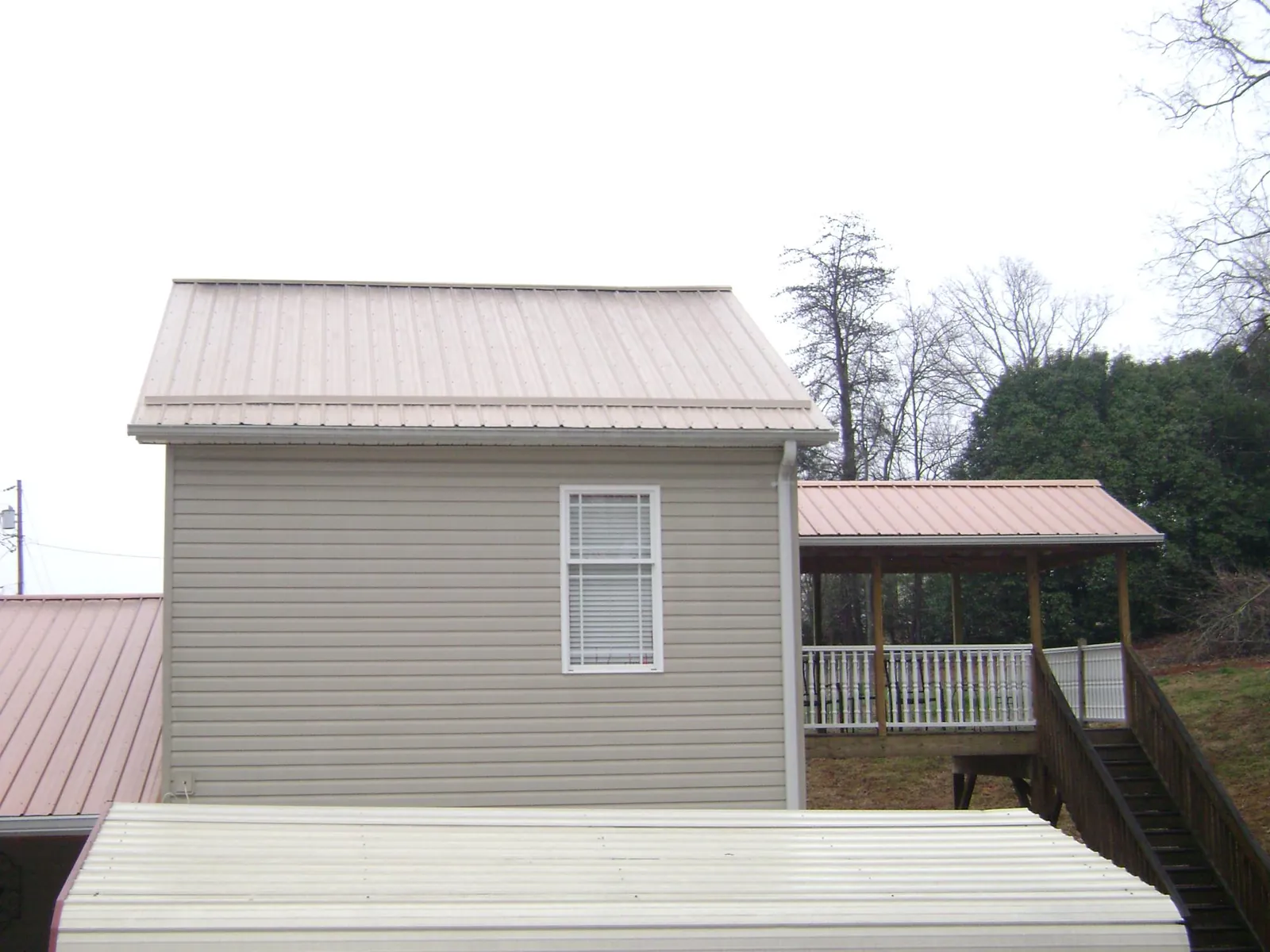 Tan metal roofs on a two story addition and attached porch, from a Roof Replacement job in Bay Pines