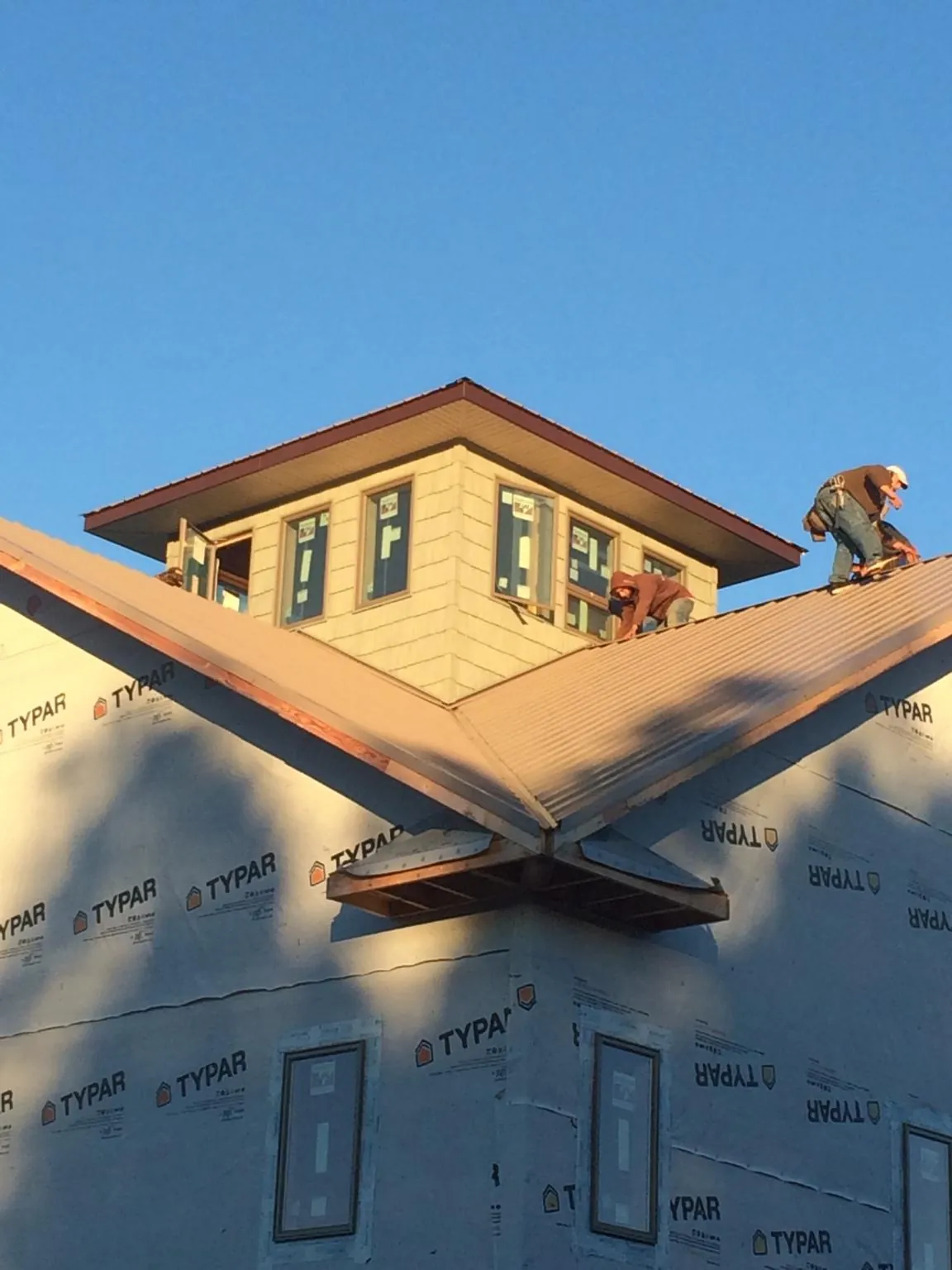 Roofers working around a rooftop cupola on a new metal roof at sunset — Roof Waterproofing in Bay Pines by Roofing Brothers